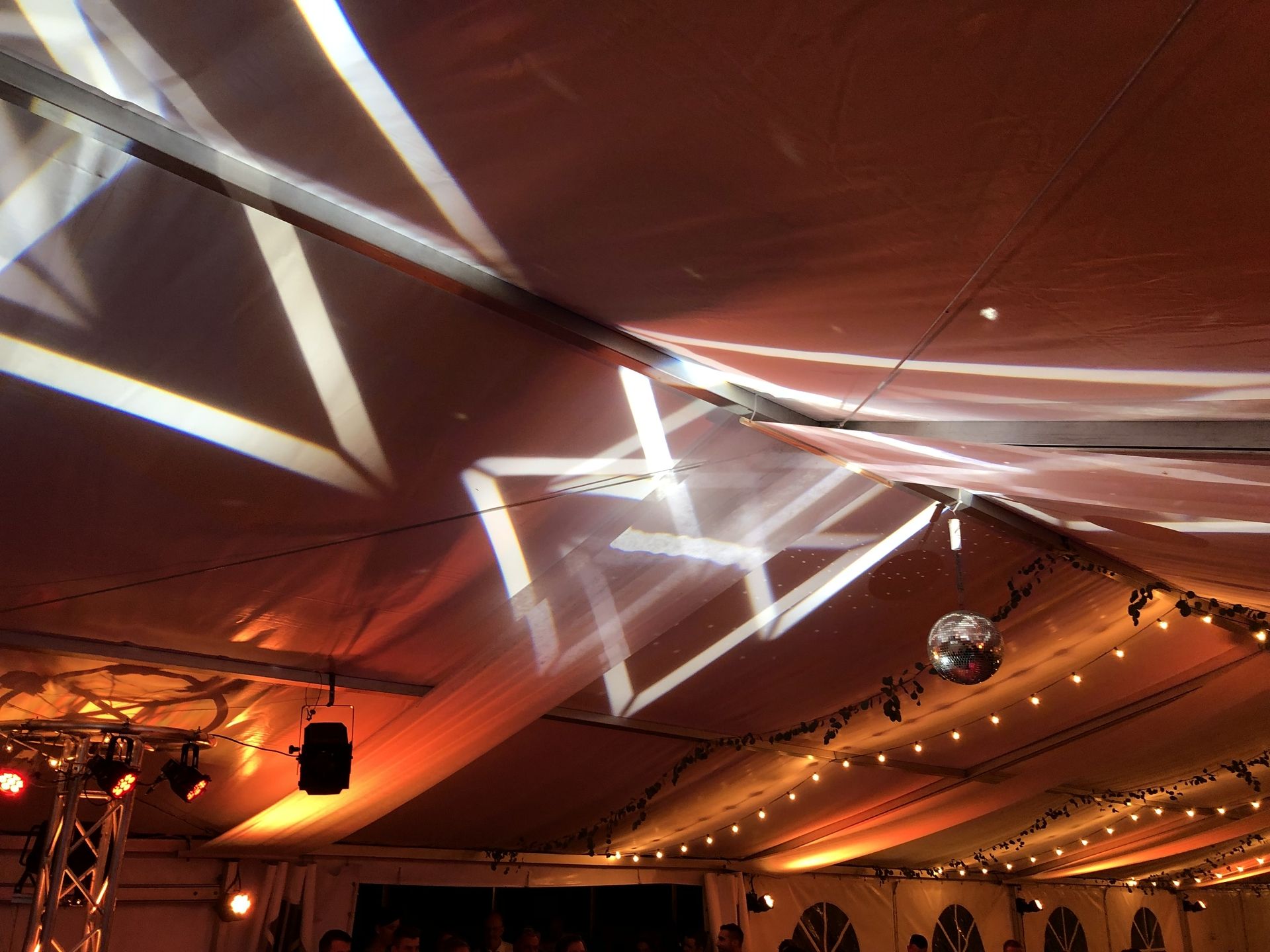 ein Festzelt mit oranger Beleuchtung und weißer Lichtshow